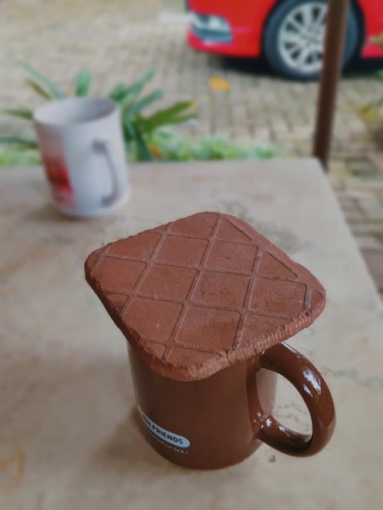 Biskuit cokelat keras di atas mug minuman di bawah pohon GKJ Pondokgede 